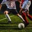 Two soccer players challenging for the ball, low angle view.